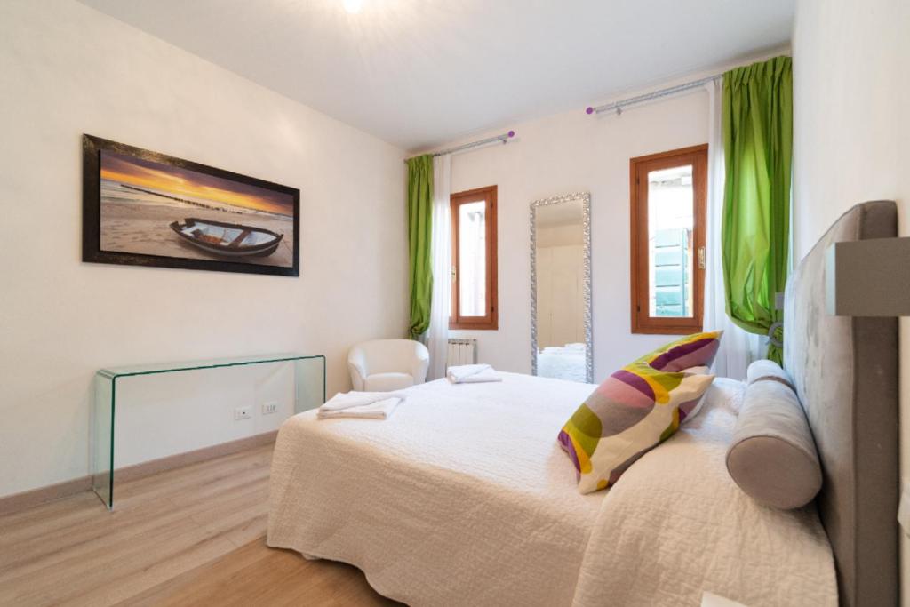 a bedroom with a large white bed with green curtains at Serenissima Apartments in Venice