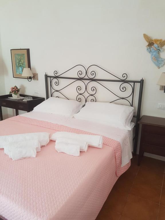 a bedroom with a pink bed with two white pillows at Masseria Gianca in Cisternino
