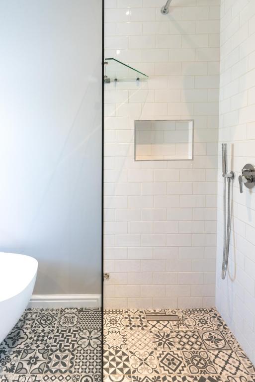 a bathroom with a shower with a tile floor at Bentley's Guesthouse in Bloubergstrand