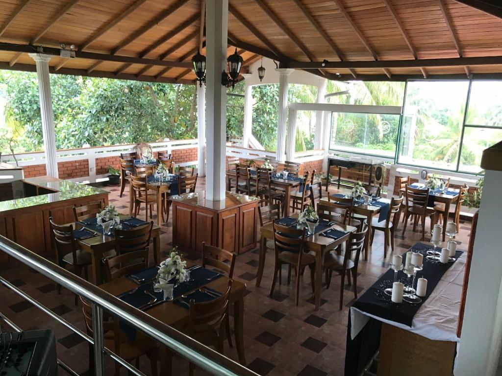 a restaurant with wooden tables and chairs and windows at Aloy's Residence in Digana
