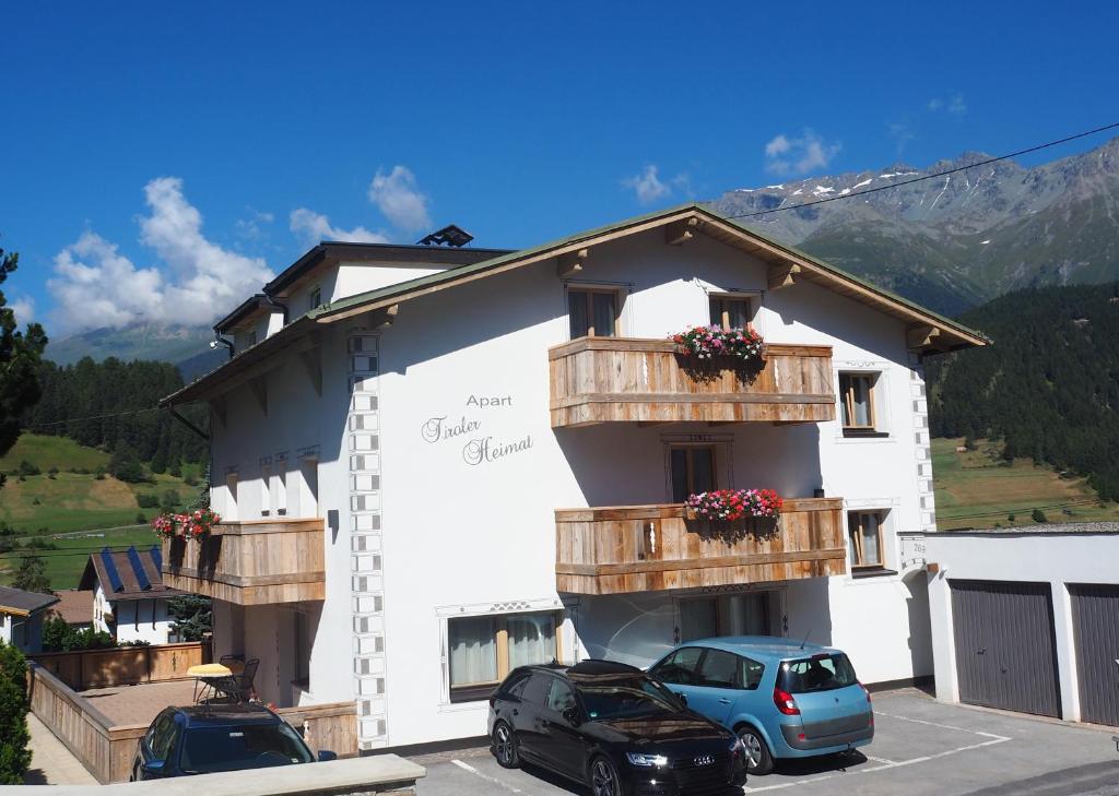ein Gebäude mit zwei Autos auf einem Parkplatz in der Unterkunft Haus Tiroler Heimat in Nauders