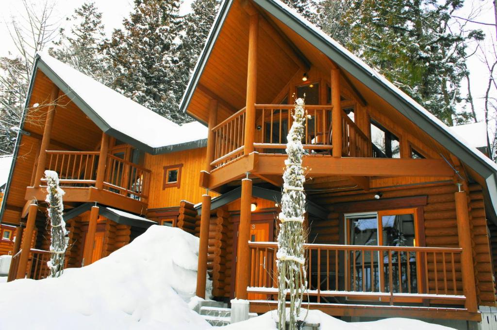 a log cabin in the snow with snow at Big Bear Chalets & Apartments in Hakuba