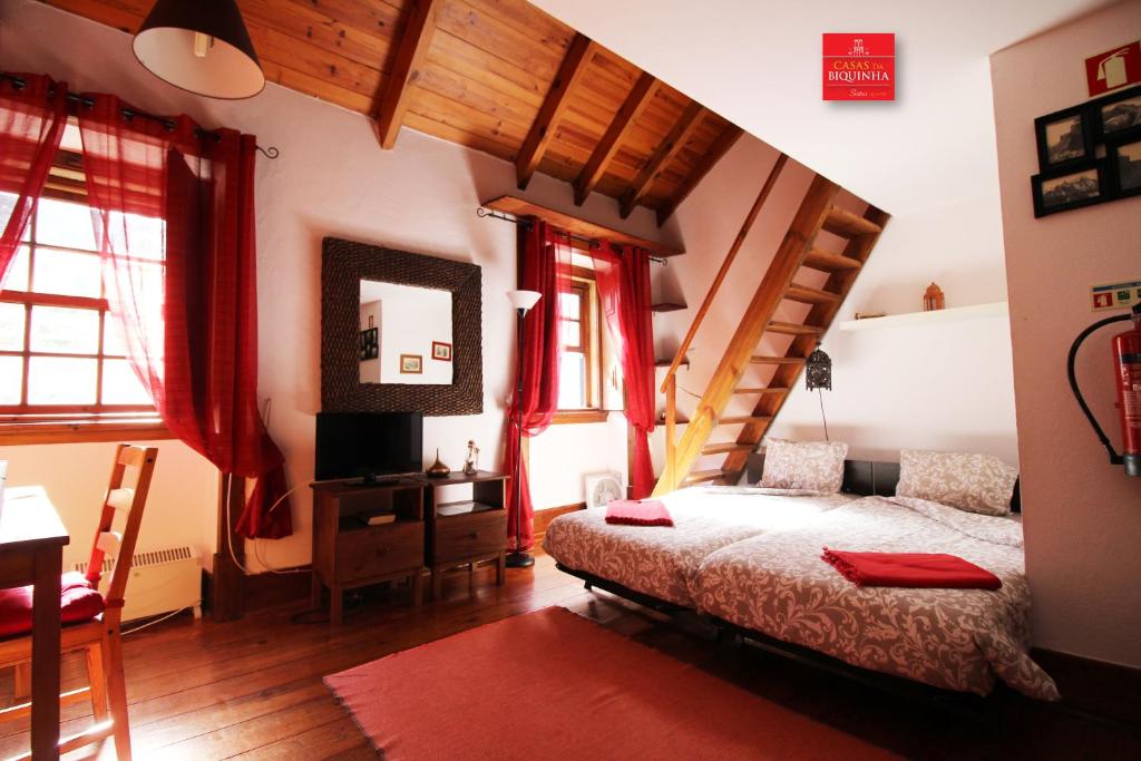a bedroom with a bed and a staircase with red curtains at Casas da Biquinha in Sintra