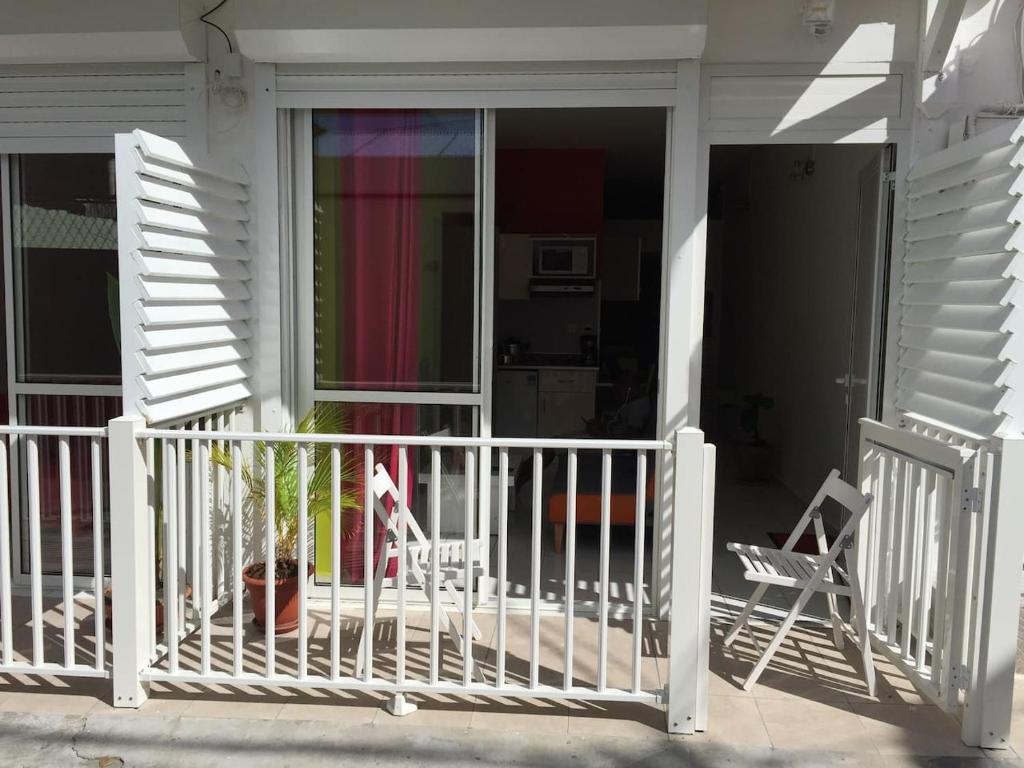 un porche con 2 sillas y una puerta de cristal en COSY Tamarins 2 plage à quelques mètres à pied, en Sainte-Anne