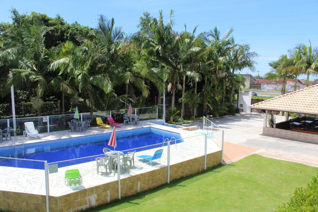 uma piscina num resort com palmeiras em Murakami Pousada em Itanhaém