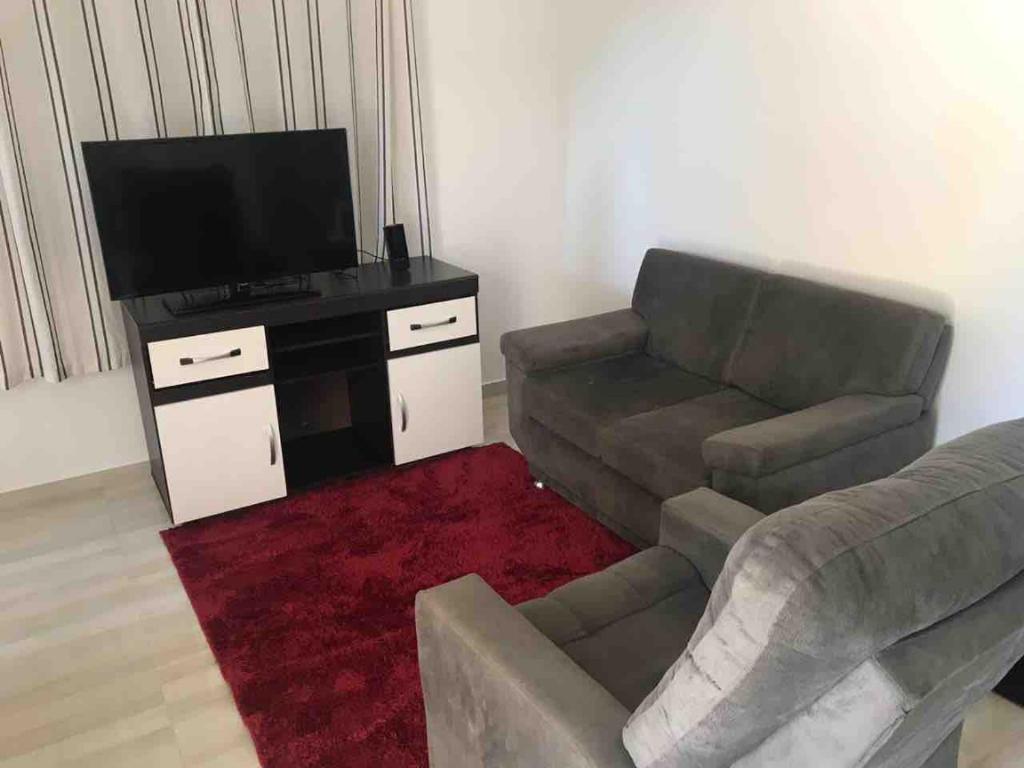 a living room with a couch and a flat screen tv at Apartamento Aconchegante em Foz in Foz do Iguaçu