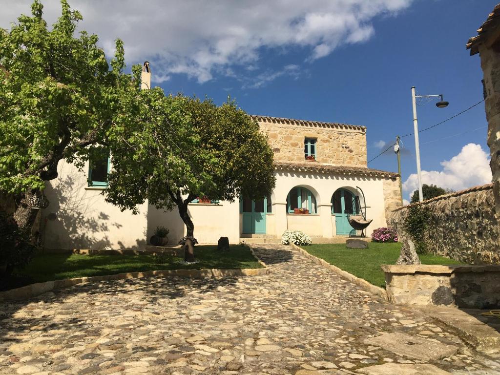 una casa con un árbol y una entrada de piedra en B&B Su Strintu, en Tuili