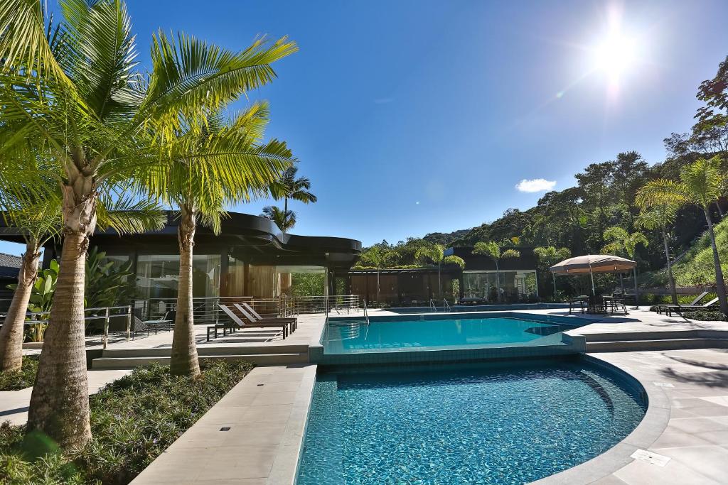 a swimming pool with palm trees in front of a house at Quality Hotel Blumenau in Blumenau
