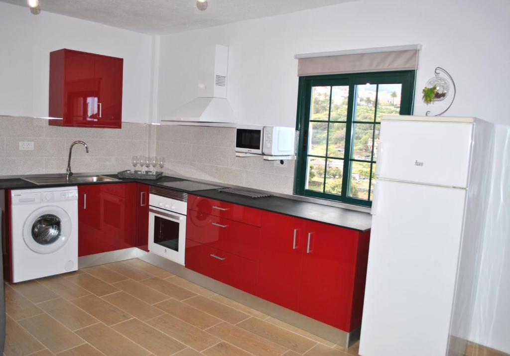 una cucina con armadi rossi e frigorifero bianco di Casa Bermudez a Breña Alta