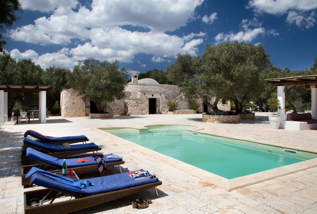 a pool with lounge chairs next to a house at Trullo Fico in Ostuni