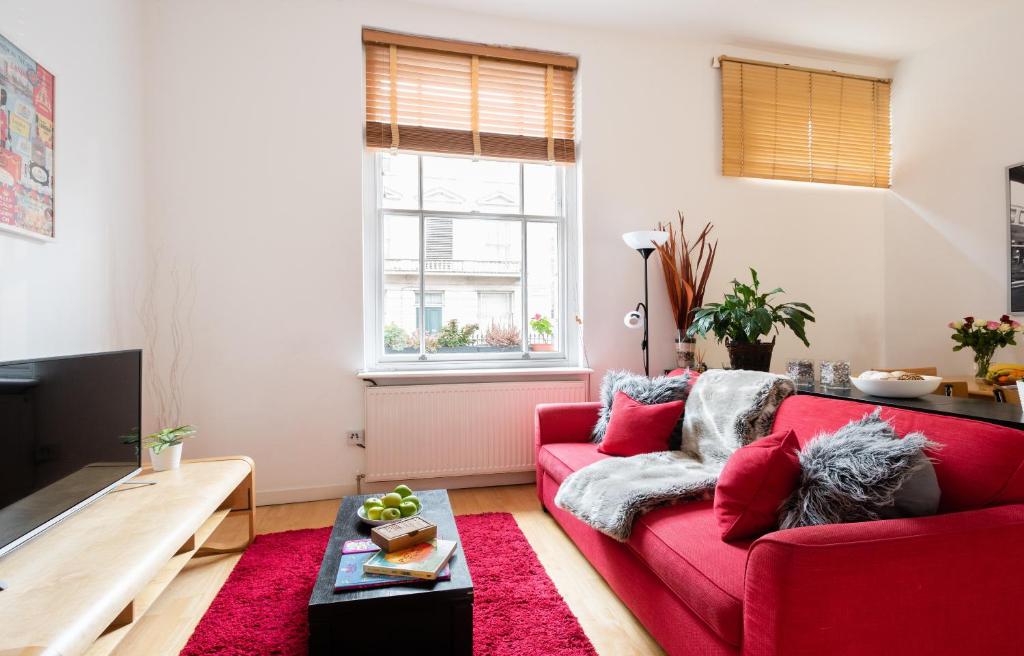 un soggiorno con divano rosso e TV di Classic Two-Bedroom Apartment Pimlico a Londra