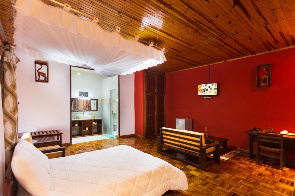 a bedroom with a white bed and a red wall at Andasibe Lemurs Lodge in Andasibe