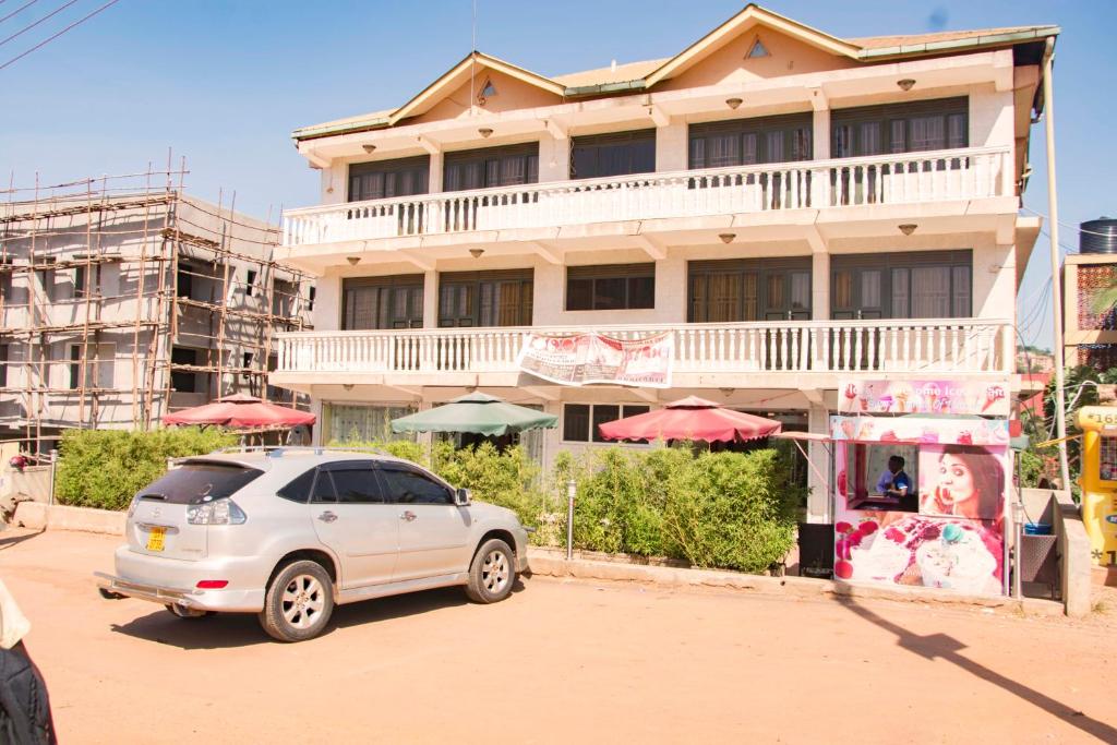 een witte auto geparkeerd voor een gebouw bij Florida Hotel Zaana Kampala in Kampala