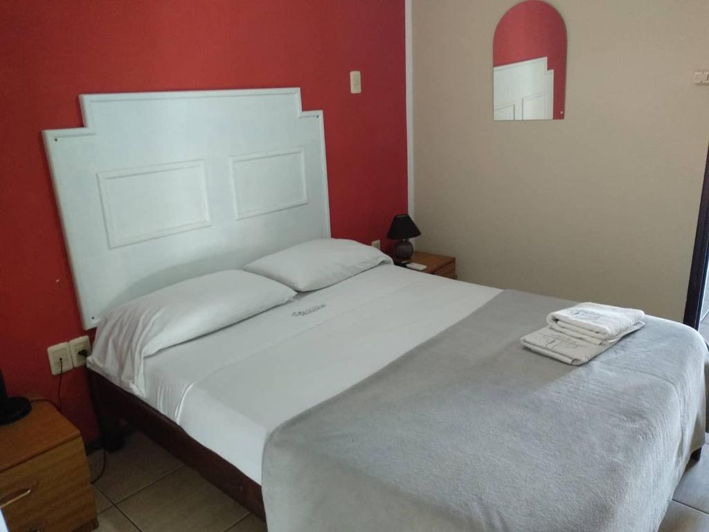 a bedroom with a large white bed with red walls at Hotel Mirador del Dayman in Termas del Daymán