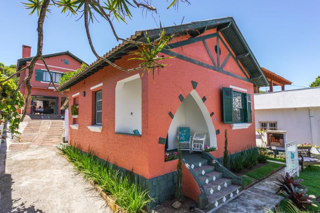 uma pequena casa vermelha com um portão em frente em Mala & Tudo Pousada em Torres