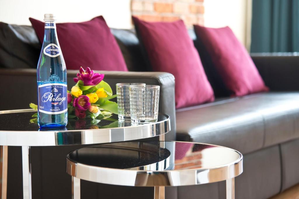 a bottle of soda and flowers on a table in a living room at Old Town Super Apartment Ogarna in Gdańsk