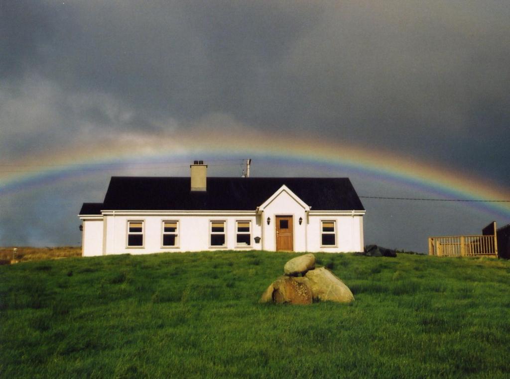 a rainbow over a white house on a hill at Ocean Bay in Malin