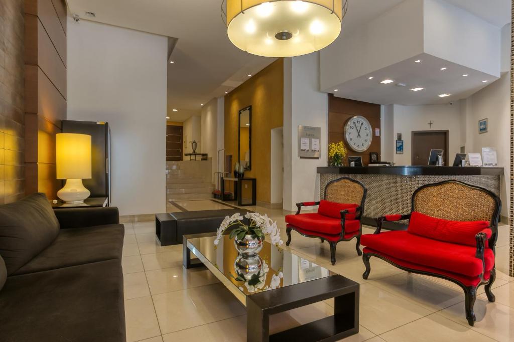 a living room with a couch and red chairs at Roochelle Hotel by Nobile in Curitiba