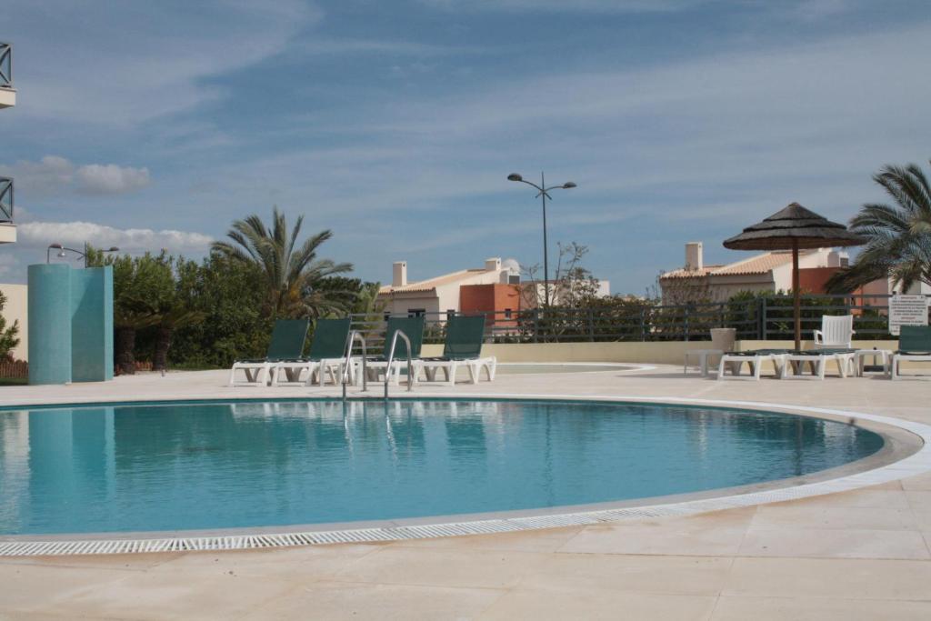 einen großen Pool mit Stühlen in der Unterkunft Apartamento com Piscina em Albufeira, Corcovada in Albufeira