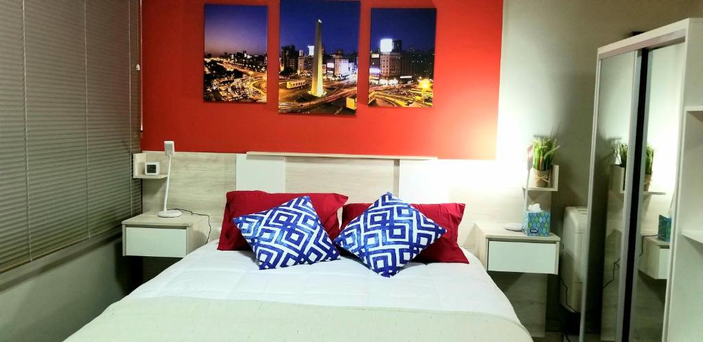 a bedroom with a bed with two blue and white pillows at Studio Harrods in Buenos Aires