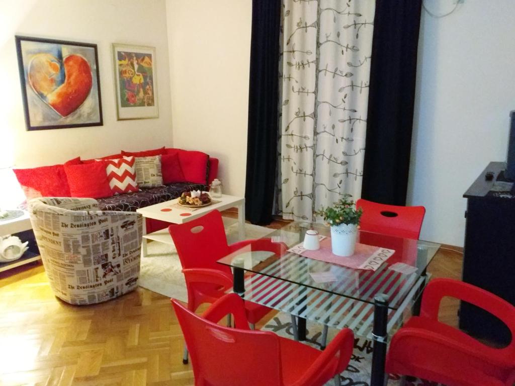 sala de estar con sillas rojas y mesa de cristal en Gold Apartments, en Belgrado