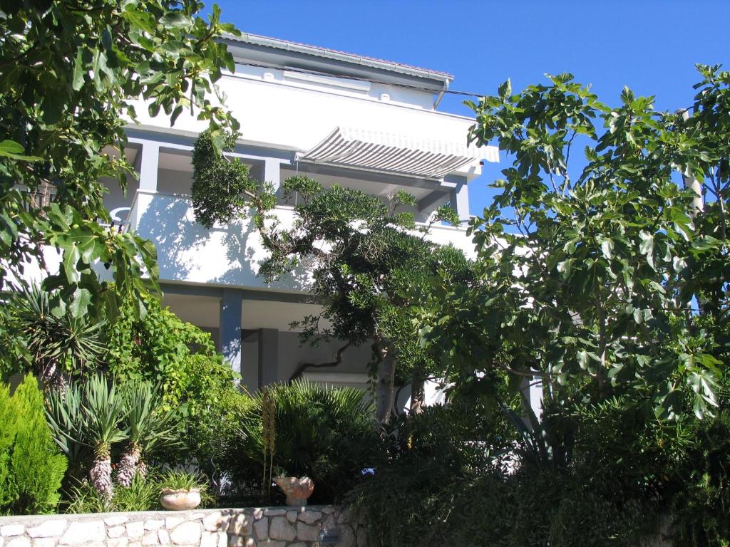 una casa blanca con árboles delante de ella en House Filomena, en Rab