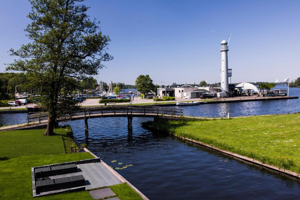 eine Brücke über einen Wasserkörper mit einem Leuchtturm in der Unterkunft B&B Lisa Groningen in Haren (Ems)