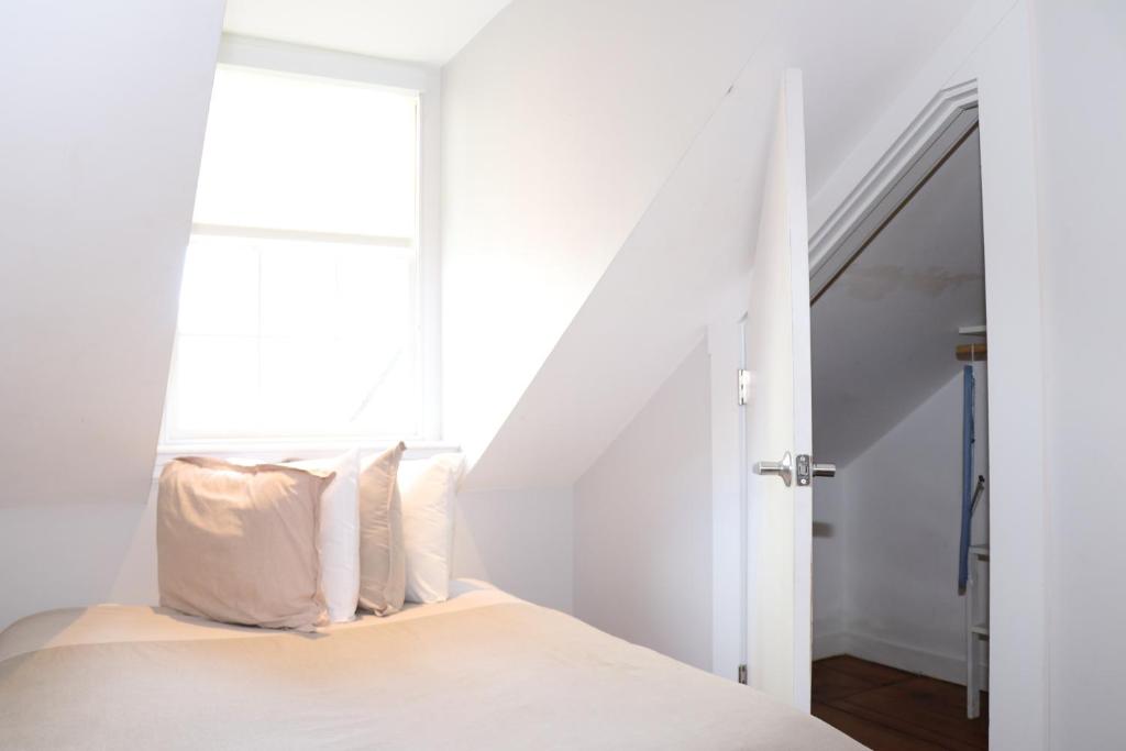 um quarto com uma cama com lençóis brancos e uma janela em Comfy Beacon Hill Studio Great for Work Travel #13 em Boston