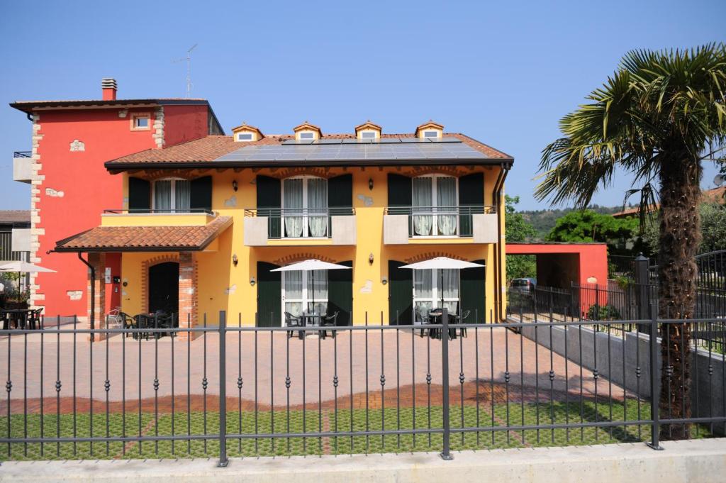 a yellow house behind a fence with a palm tree at Agriturismo Terra E Sole in SantʼAmbrogio di Valpolicella