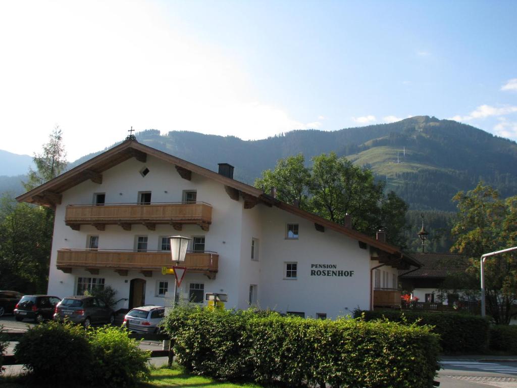 a large white building with a mountain in the background at Pension Rosenhof in Brixen im Thale