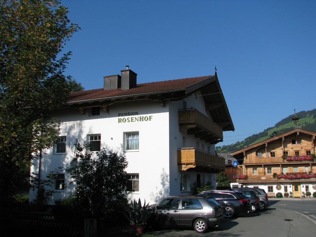 a white building with cars parked in a parking lot at Pension Rosenhof in Brixen im Thale