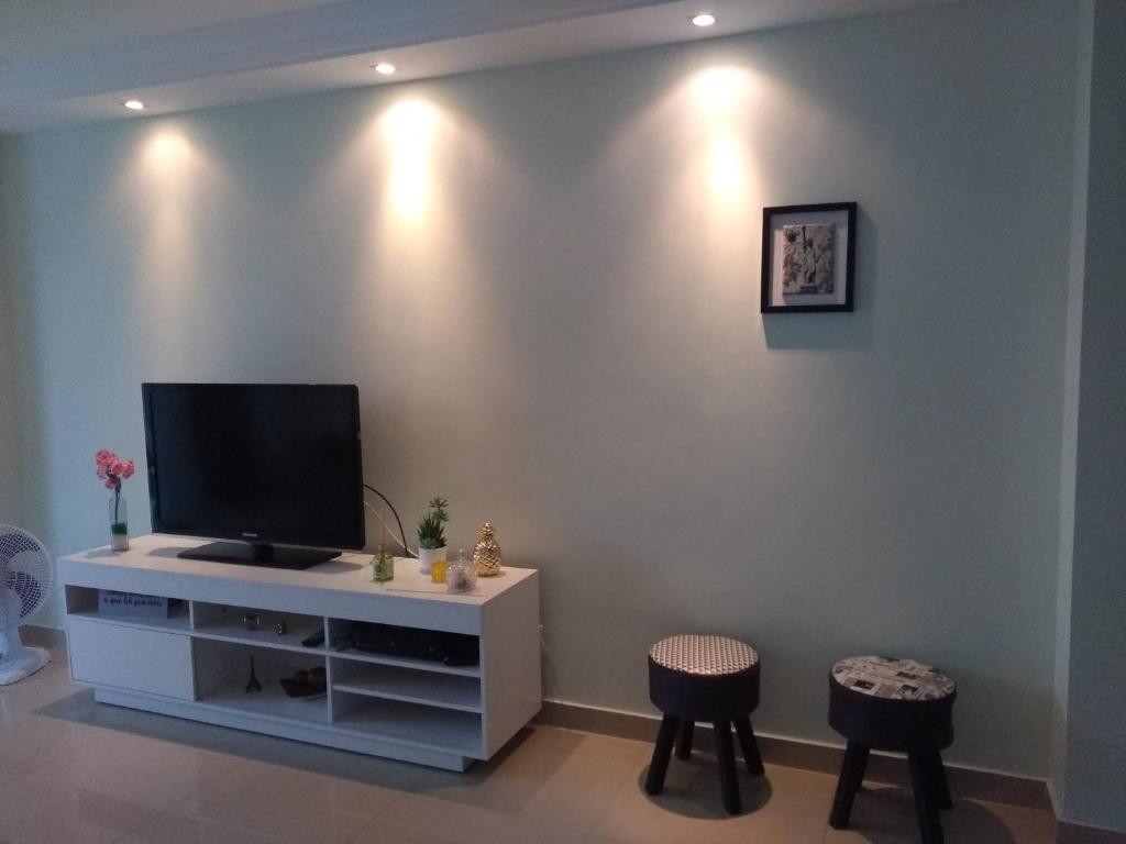 a living room with a tv on a wall with stools at Apartamento frente ao mar in Saquarema