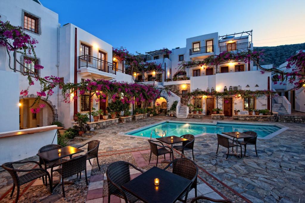 a hotel patio with tables and chairs and a swimming pool at Villa Diktynna in Hersonissos