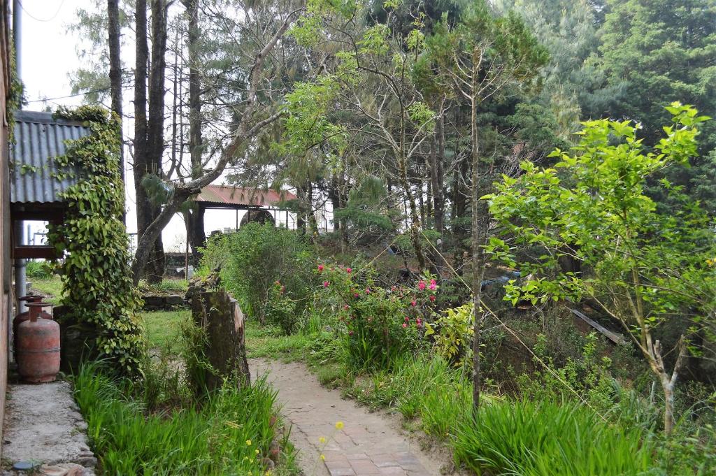 a path through a garden with a bridge in the background at Hotel At The End Of The Universe in Nagarkot