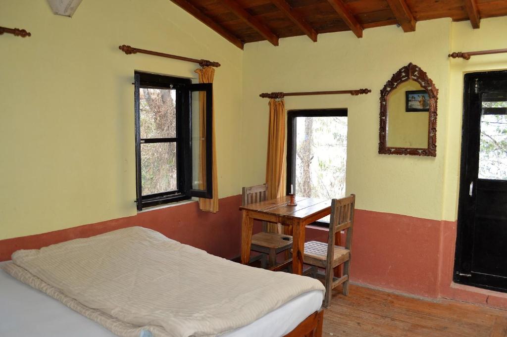 a bedroom with a bed and a table and windows at Hotel At The End Of The Universe in Nagarkot