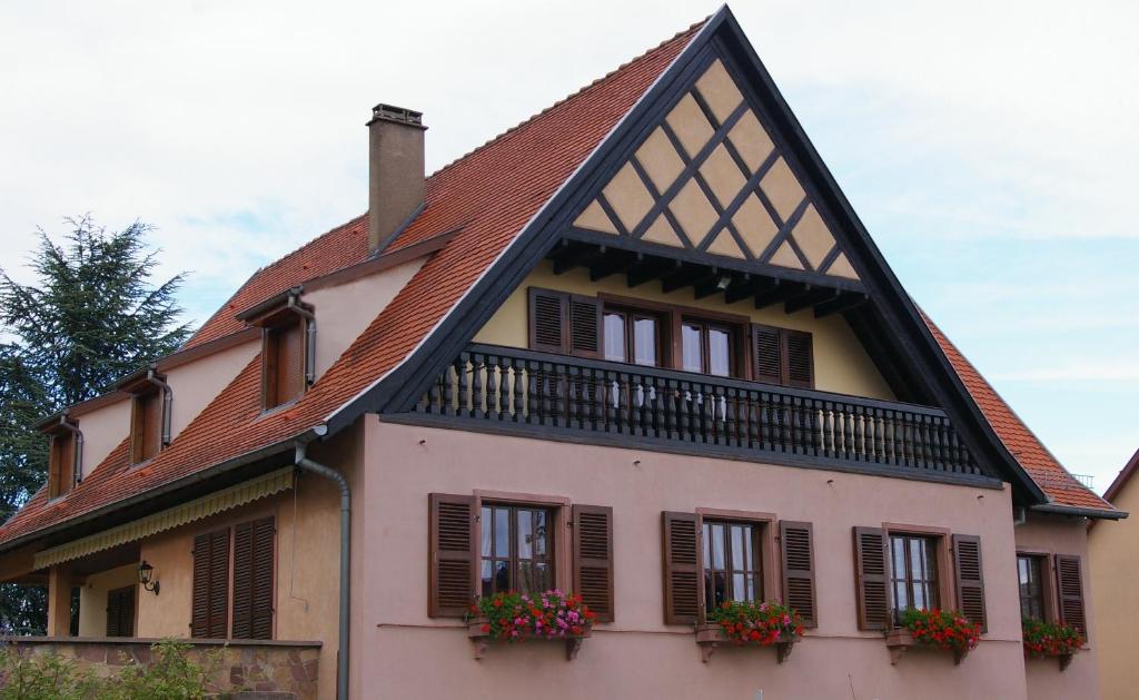 a house with a gambrel roof and windows with flower boxes at Gite Chez Jean in Saint-Hippolyte