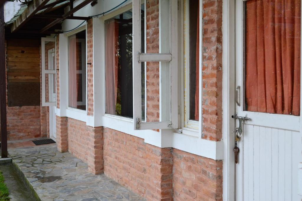 a brick building with a white door and windows at Hotel At The End Of The Universe in Nagarkot