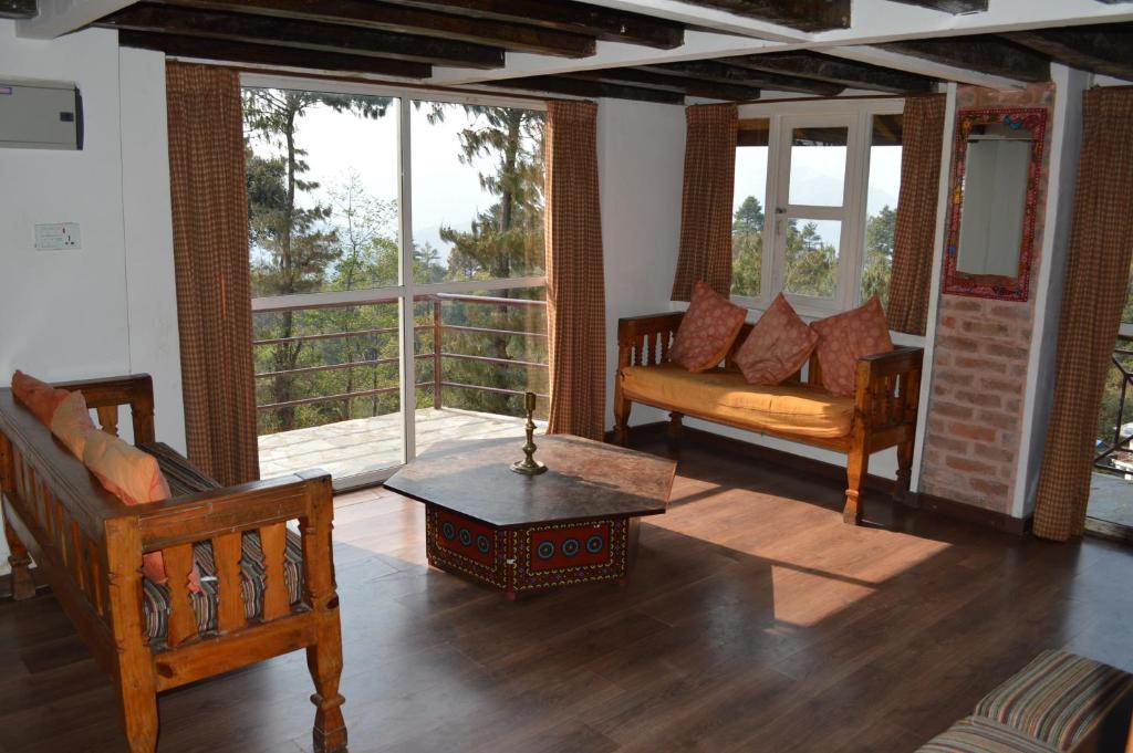 a living room with wooden furniture and a balcony at Hotel At The End Of The Universe in Nagarkot