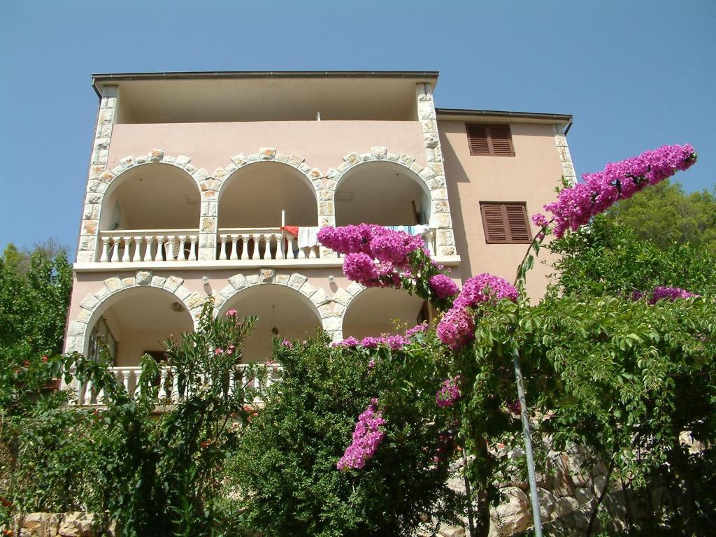 een roze gebouw met paarse bloemen ervoor bij Apartments Bosnic in Prizba