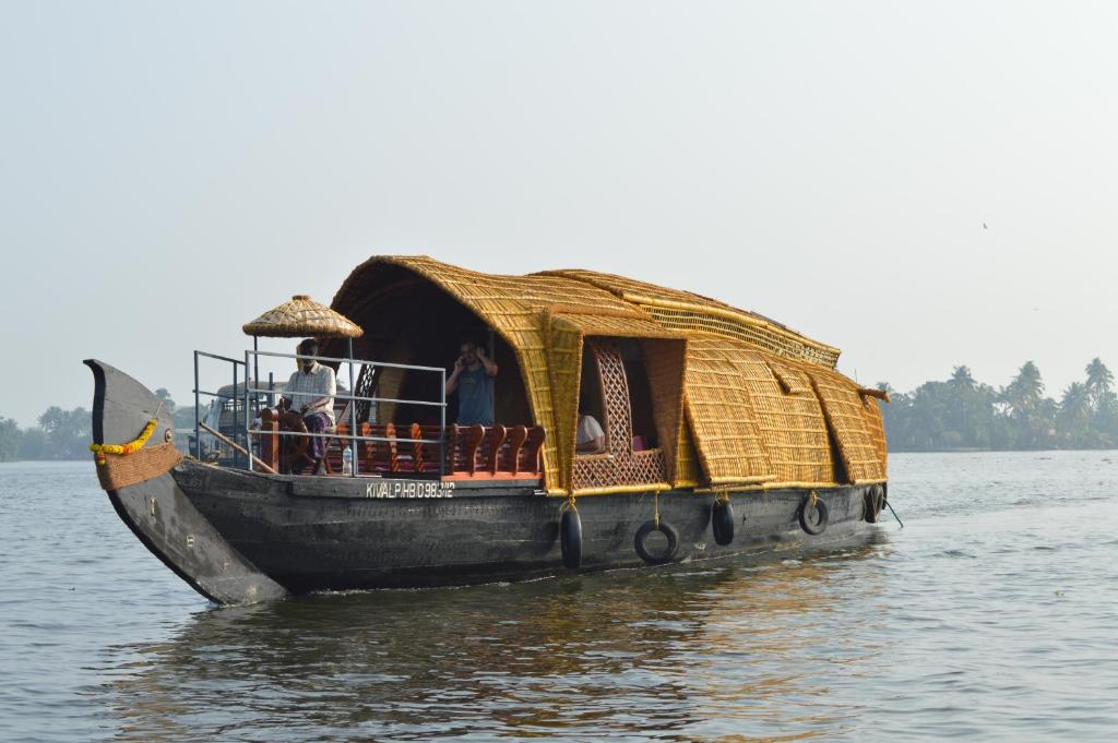 a boat with a straw roof on the water at Thara's Houseboat in Alleppey