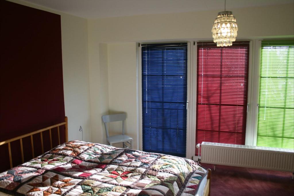 um quarto com janelas vermelhas e azuis e uma cama em Gästeapartment Gasthaus Lege em Burgwedel