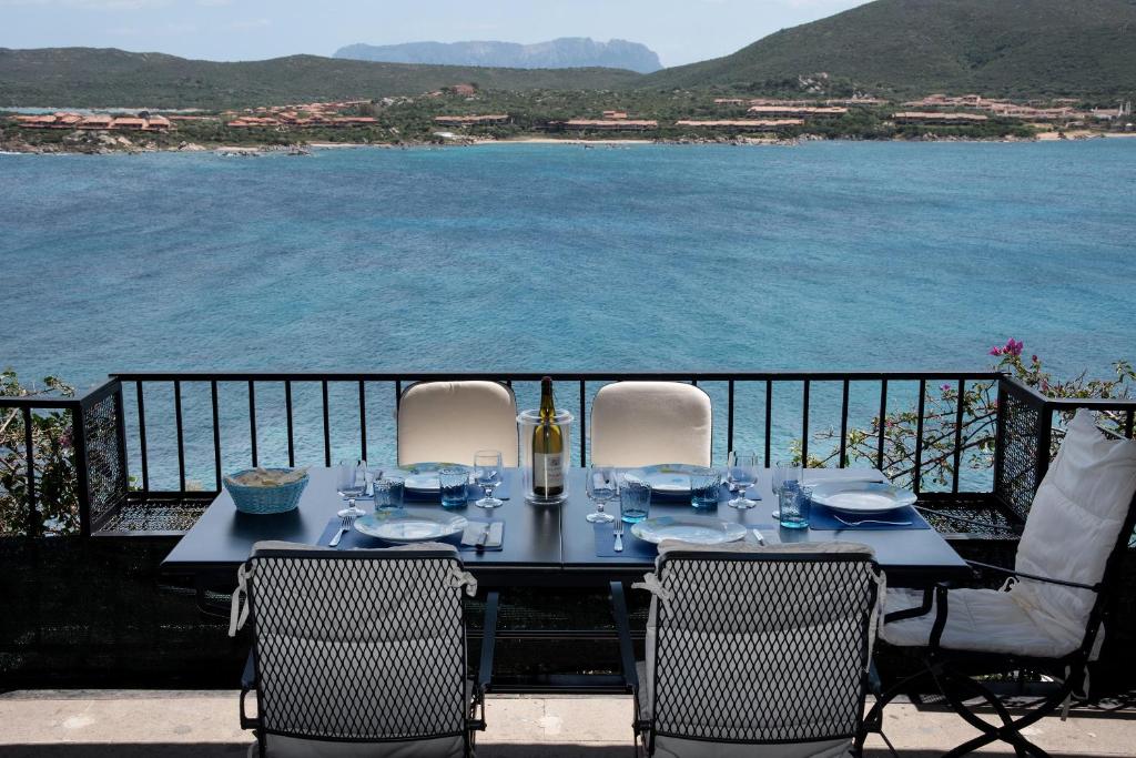 a dining table with chairs and a view of the water at Casa Valery Wonderful Sea View in Porto Rotondo