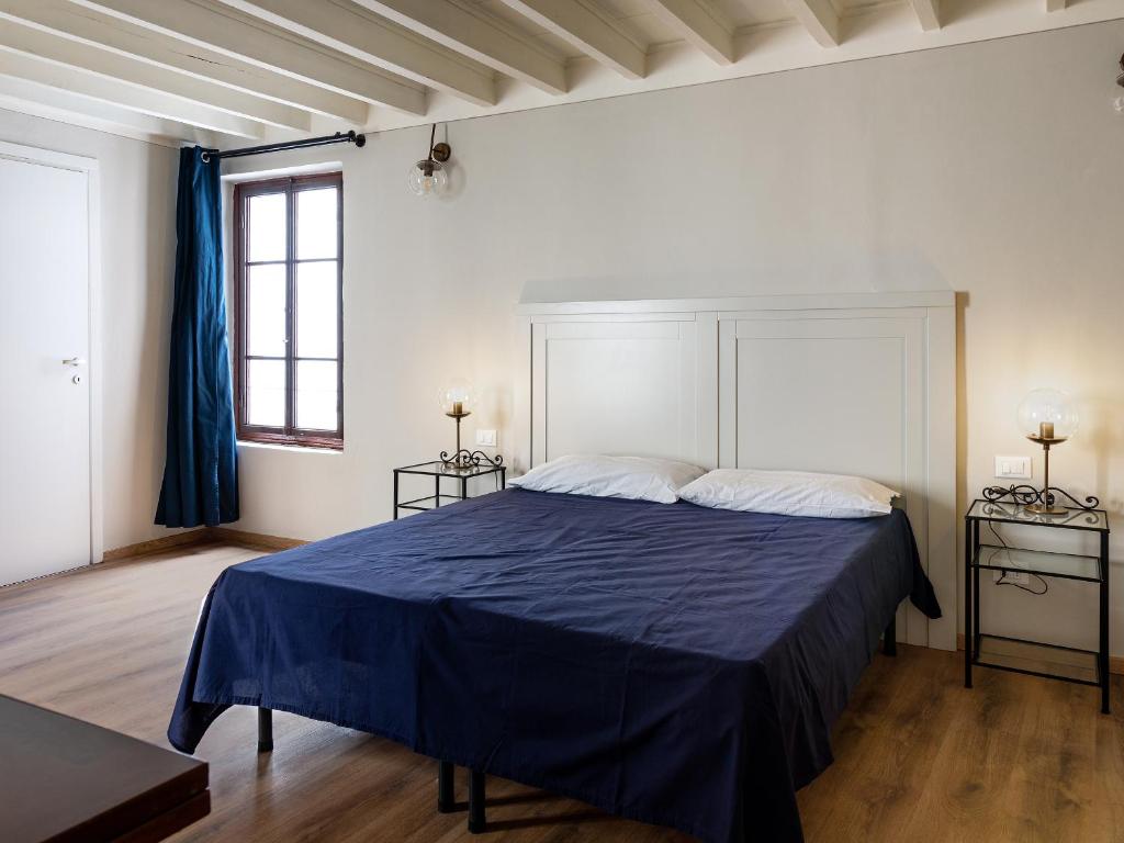 a bedroom with a blue bed with two windows at B&B Stupido Hotel in Florence