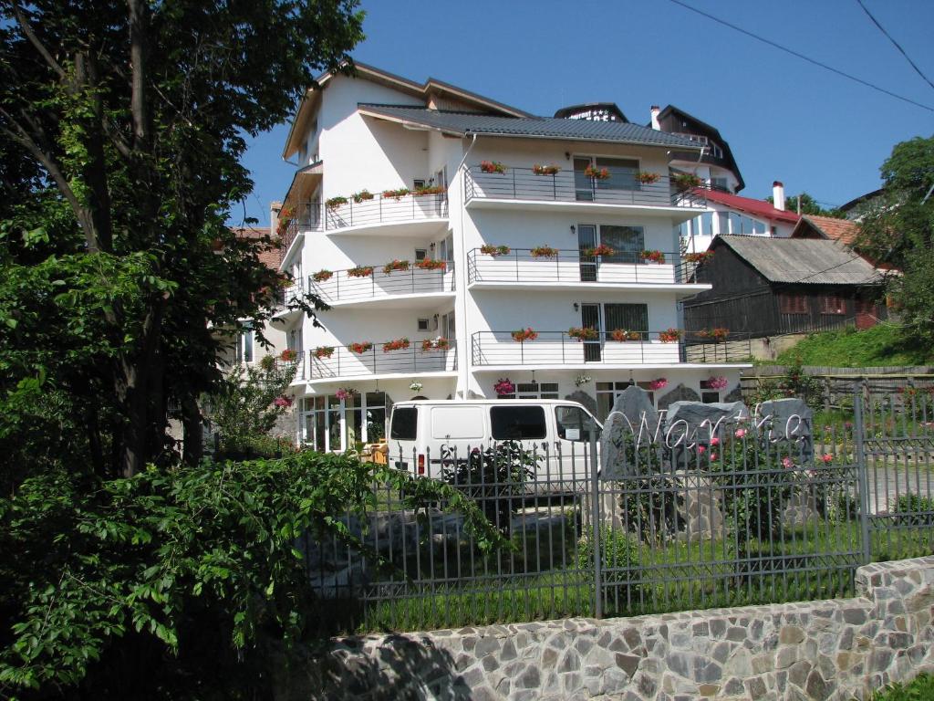 um edifício branco com um camião estacionado em frente em Pensiunea Warthe em Brasov