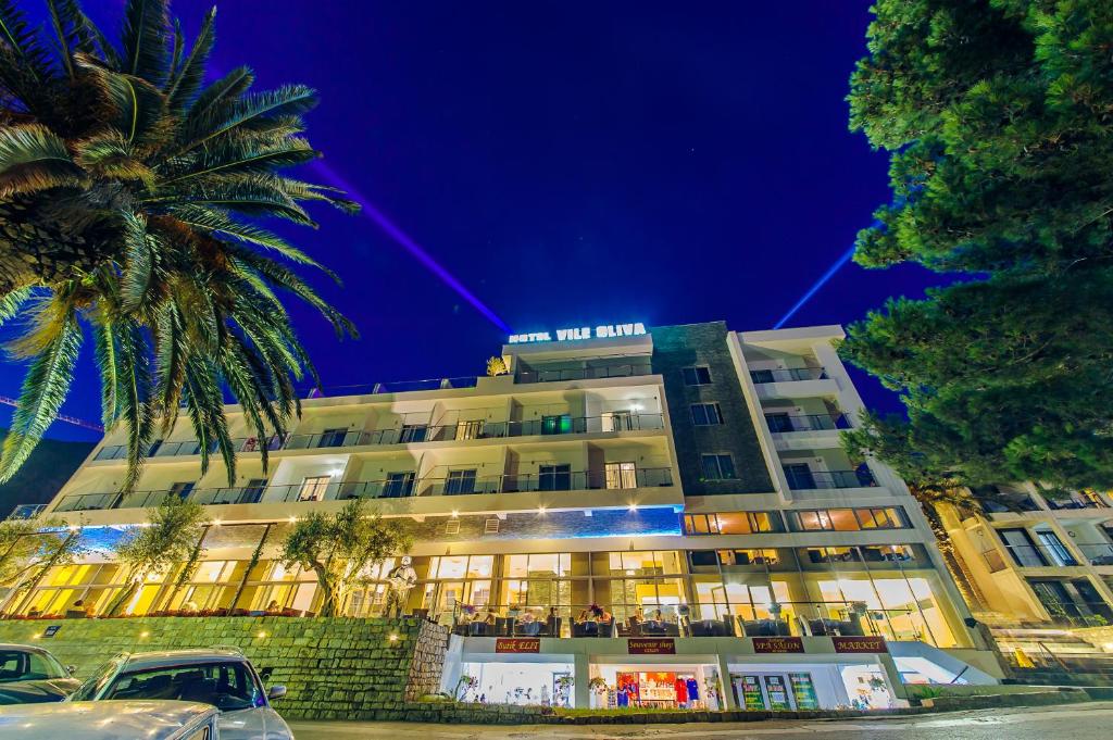 a building with a palm tree in front of it at Vile Oliva Hotel & Resort in Petrovac na Moru