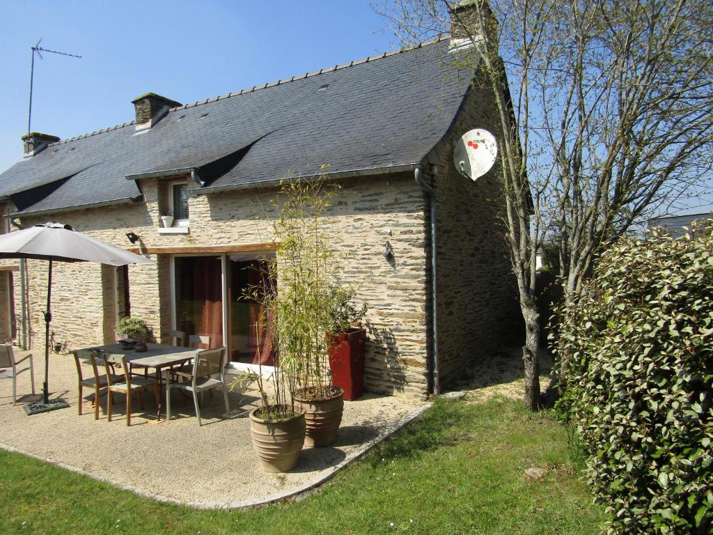 a stone house with a table and an umbrella at Gite les Camélias in Sainte-Anne-sur-Vilaine