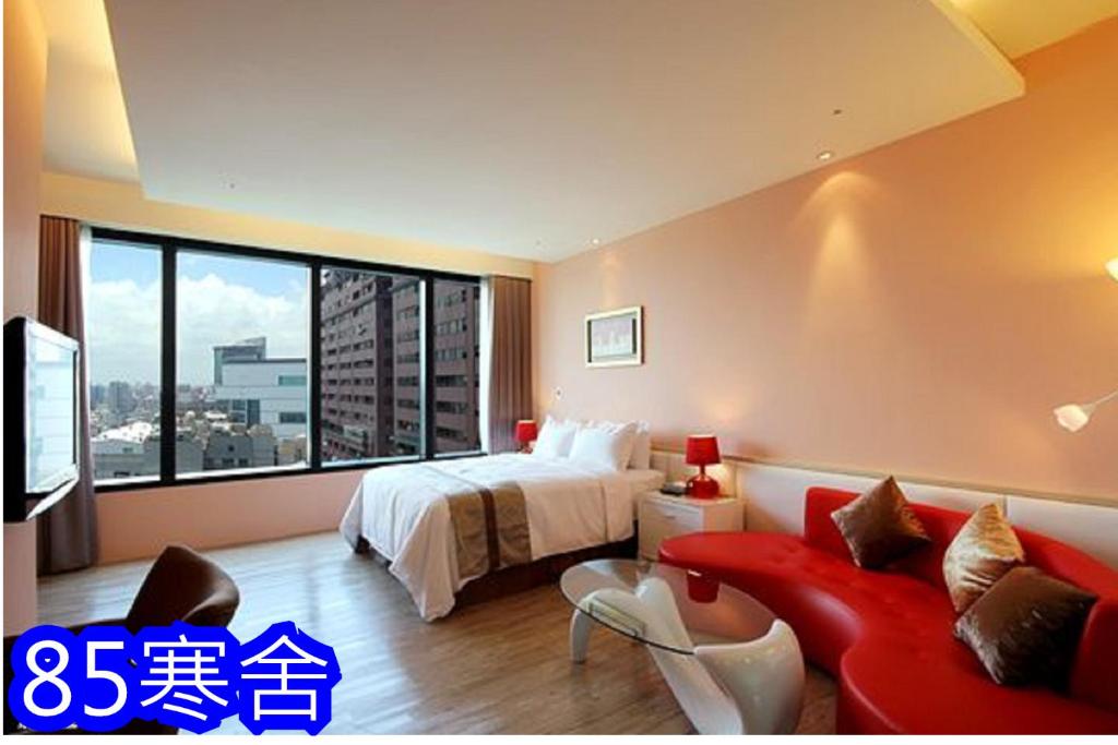 um quarto de hotel com uma cama e um sofá vermelho em 85涵舍旅宿 em Kaohsiung