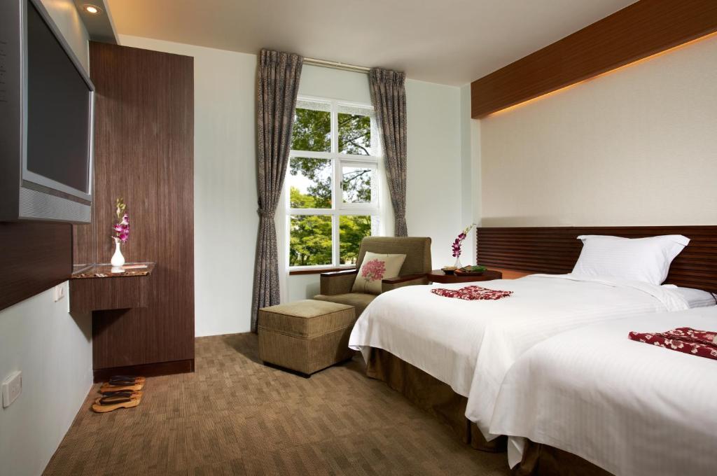 um quarto de hotel com duas camas e uma televisão em Hua Ge Hot Spring Hotel em Jiaoxi