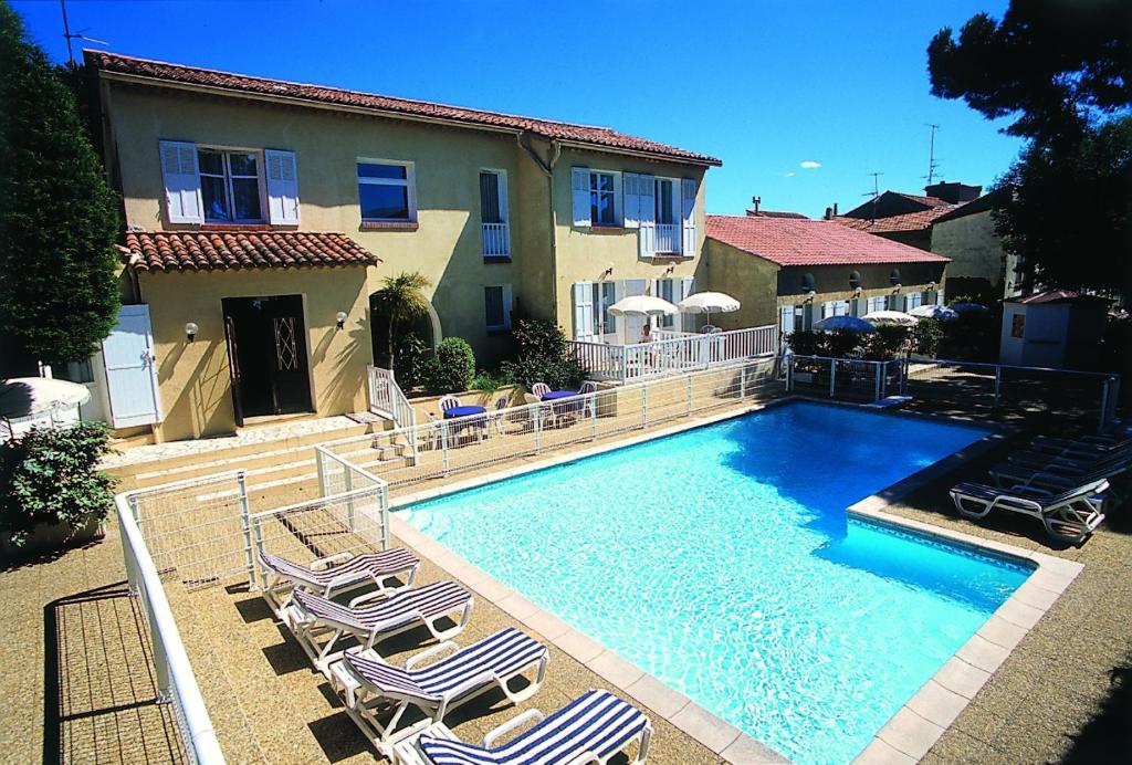 a swimming pool with lounge chairs and a house at Hôtel Lou Paouvadou in Sainte-Maxime