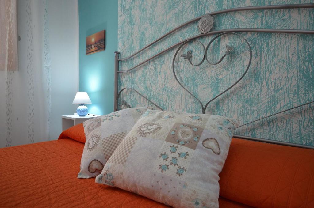サン・ヴィート・ロ・カーポにあるCase vacanza Gioeleのベッドルーム(オレンジ色のベッド、金属製ヘッドボード付)